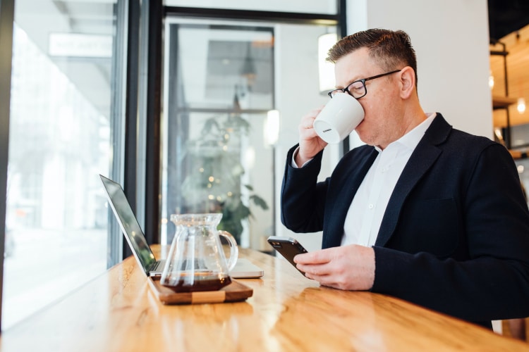 photo of a salesperson drinking coffee while checking email