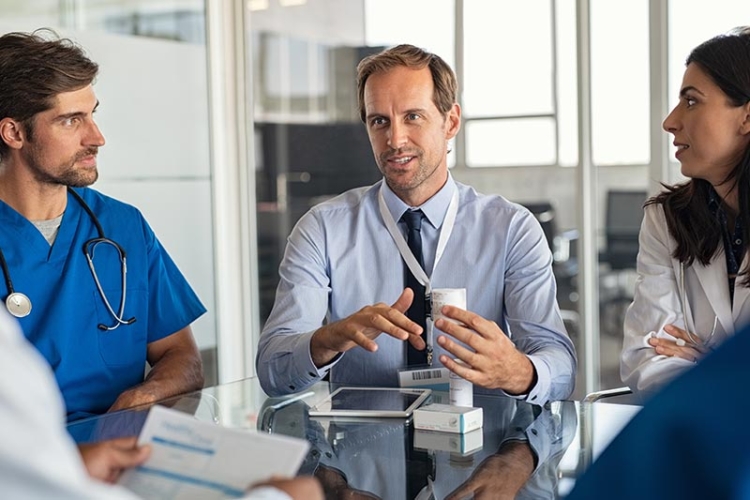 A medical device sales rep talking to a doctor in a hospital about the benefits of a medical device