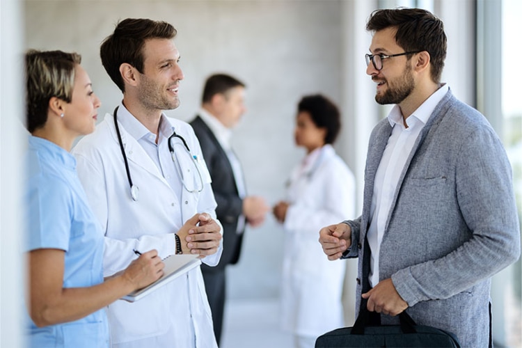 A medical device sales rep talking to a doctor in a hospital