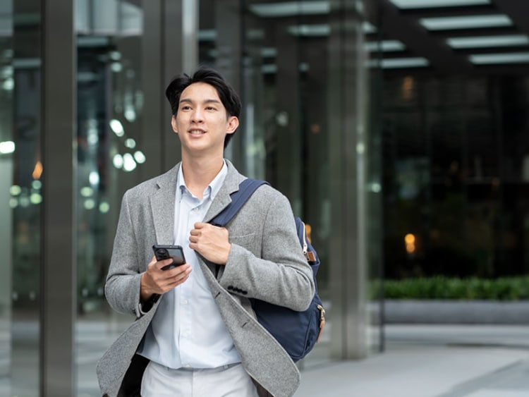 A sales rep walking and using a route optimization app on his smartphone to locate his client's office.
